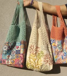 three purses are lined up on the ground with one being held by someone's arm