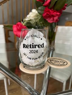 a wine glass sitting on top of a table next to a vase filled with flowers