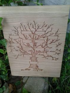 a wooden plaque with a family tree on it in front of some grass and rocks