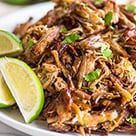 a white plate topped with shredded meat and limes