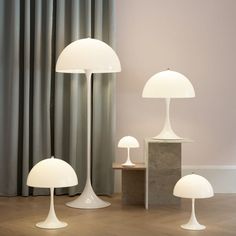 three white lamps sitting next to each other on top of a wooden floor