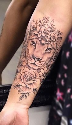 a woman's arm with a tiger and roses tattoo on her left forearm, while another person holds out their hand