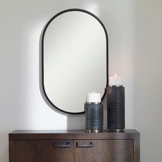 a mirror sitting on top of a wooden dresser next to a lit candle in front of it