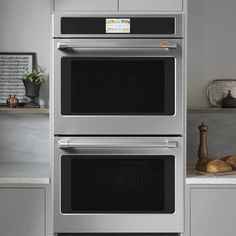 two stainless steel ovens side by side in a kitchen with white cabinets and counter tops