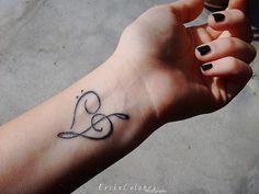 a woman's arm with a heart tattoo on the left side of her hand