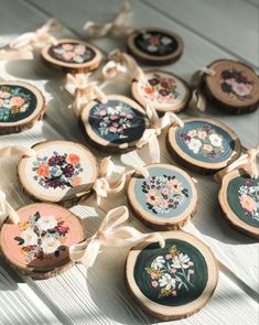 several pieces of wood with flowers painted on them and ribbons tied around the edges, sitting on a table