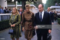 two women and a man are walking down the street with other people in the background