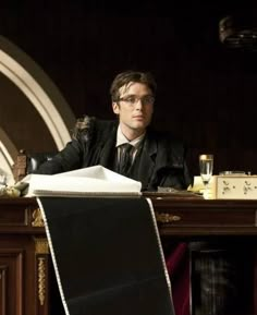 a man sitting at a desk with a book in front of him