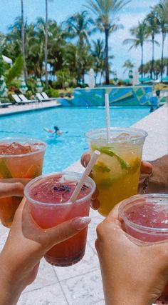 people holding up drinks near a swimming pool