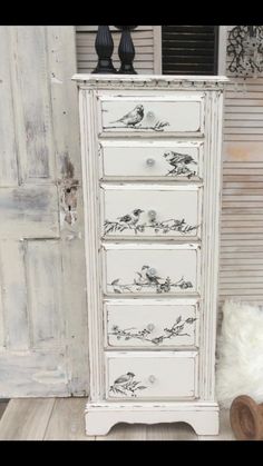 an old white dresser with black and white designs on the drawers is sitting in front of a door