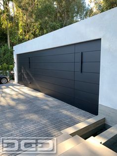 a car parked in front of a white building with black garage doors on the side