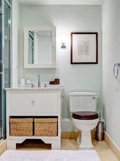 a white toilet sitting next to a sink in a bathroom under a framed picture on the wall