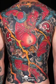 the back of a man's body with tattoos on it and an image of a demon