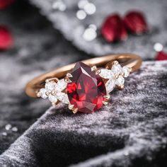 a close up of a ring with a red stone in the middle and white stones around it