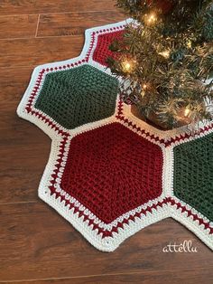 a crocheted christmas tree skirt is on the floor next to a pot holder