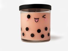 a pink candle with black polka dots and a smile on it's face is sitting in front of a white background