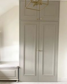 an empty room with two gray cabinets and a bench in front of the closets