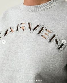 a woman wearing a grey sweatshirt with the word'beware'embroidered on it