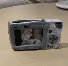 a small toy television with a face on it's screen and an image of a woman behind the screen