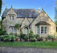 an old stone house with potted plants in the front yard and windows on each side