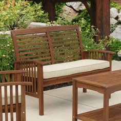 a wooden bench sitting next to a small table with a pillow on top of it