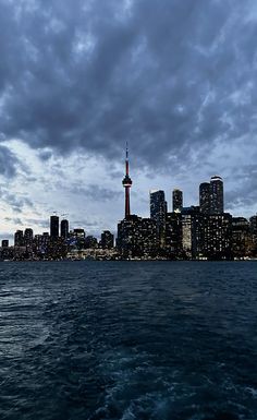 the city skyline is lit up at night as seen from the water's edge