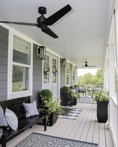 a porch with black and white furniture and plants on the front porch, along with blue rugs