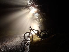 a bike parked on the side of a road in the dark with sunbeams