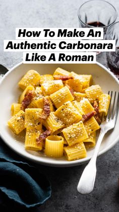 pasta with bacon and parmesan cheese in a bowl next to two glasses of wine