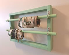 a green rack with bracelets hanging from it's sides on a white wall