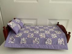 a bed with purple bedspread and pillows on it in front of a door