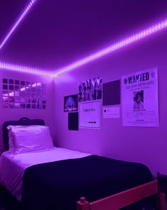 a bed in a room with purple lights on the ceiling and posters hanging above it