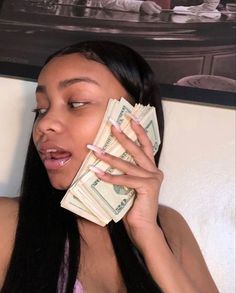 a woman talking on a cell phone while holding money