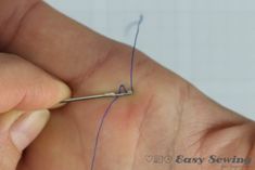 a person is holding a needle in their left hand and threading it on the other hand