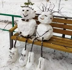 two snowmen sitting on top of a wooden bench