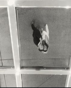 an overhead view of a man laying on the ground in front of a glass wall