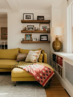 a living room with a yellow couch and bookshelves on the wall above it