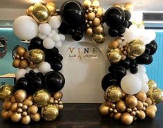 a table topped with balloons and black and gold decorations