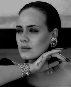 black and white photograph of a woman with her hand on her shoulder, wearing jewelry