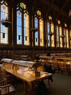 people sitting at tables in a library with stained glass windows