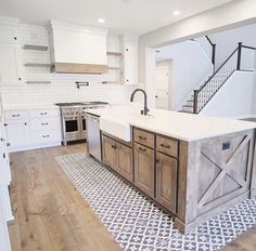 a large kitchen with an island in the middle and stairs leading up to the second floor