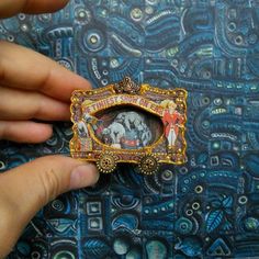 a person is holding a brooch with pictures on it