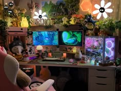 a desk with multiple monitors and stuffed animals on it, all lit up by colorful lights