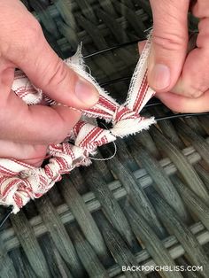 two hands are working on something that is red and white with some fraying around it