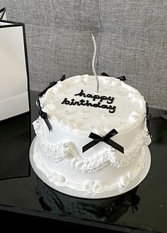 a white birthday cake sitting on top of a table next to a black and white card