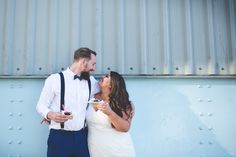 a man and woman standing next to each other in front of a blue metal wall