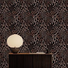 an animal print wallpaper with a lamp on the sideboard in front of it