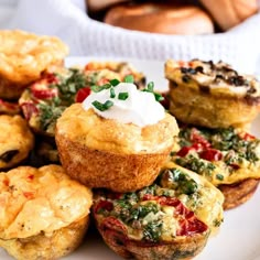 several small muffins on a white plate topped with sour cream and spinach