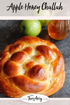 an apple honey challah on a plate next to some apples and a cup of tea