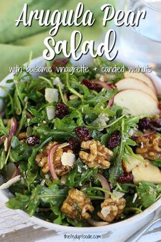 a salad with apples, walnuts and cranberries in a white bowl on a table